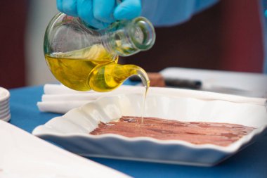 Bir el ançüez tepsisine zeytinyağı döker..