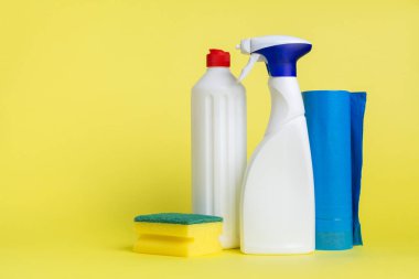 İki kutu temizlik spreyi ve sarı bir arka plana yerleştirilmiş çöp torbası.