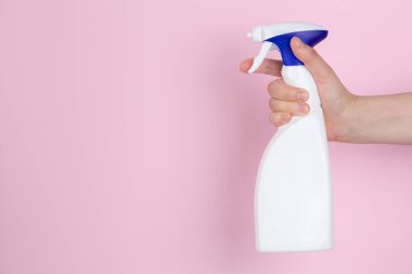 Pembe arka planda sprey sıkan bir kadın eli.