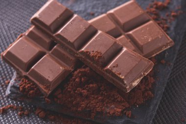 Kakao tozu ve siyah arkaplan üzerine parçalanmış çikolata.