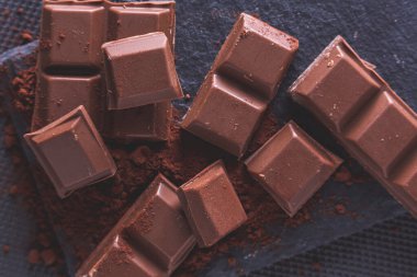 Kakao tozu ve siyah arkaplan üzerine parçalanmış çikolata.