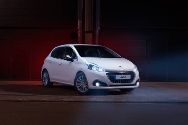 Beyaz Peugeot 208 Bluehdi park halinde, ön taraftan gece ve ışıklar açıkken görüldü..