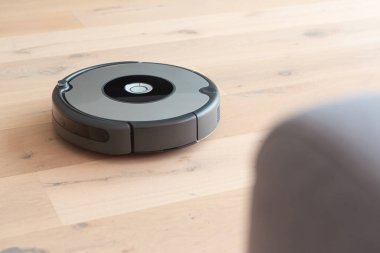 Robot elektrik süpürgesi ahşap zemini temizliyor.