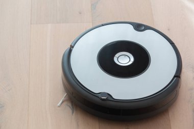 Robot elektrik süpürgesi ahşap zemini temizliyor.