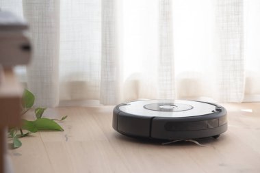 Robot elektrik süpürgesi ahşap zemini temizliyor.