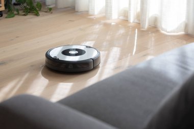 Robot elektrik süpürgesi ahşap zemini temizliyor.