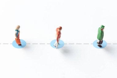 Beyaz arka planda minyatür insan figürleri ve yerde de güvenlik mesafesi var.