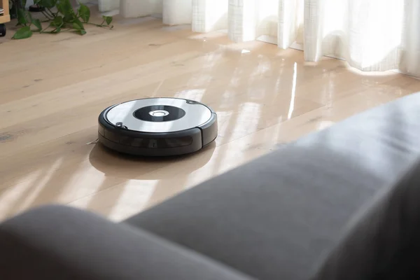 Robot elektrik süpürgesi ahşap zemini temizliyor.