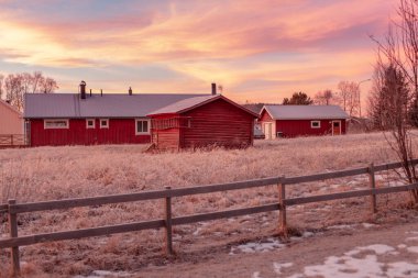 Jukkasjrvi, İsveç - 19 Kasım 2018. Laponya 'da tipik bir İsveç çiftliği, ahşaptan yapılmış ve kırmızıya boyanmış. Donmuş manzarayla gün batımında.