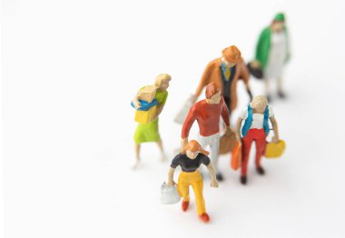 Beyaz arka planda alışveriş yapan çantalı minyatür figürler.