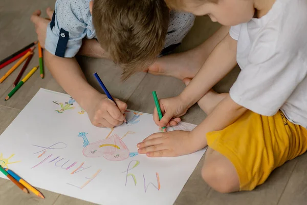 Children paint a picture of their family. The inscription My Family. The figure shows people, family members, heart. Draw two brothers, boys. Teamwork together. The concept of love in the family, friendly family