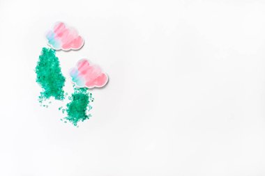 Beyaz arka planda mavi ve pembe renkli iki kağıt bulut. Bunlardan, turkuaz banyo tuzundan yağmur yağar. Mesaj için yer var. Spa ve rahatlama kavramı.