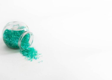 Şeffaf bir kavanoz ve turkuaz banyo tuzu. Beyaz arka planda yatay fotoğraf. Kişisel bakım ve spa için aksesuar konsepti. Bankalar yan yatar. Metin için boşluk.