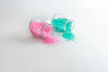 Açık pembe ve turkuaz banyo tuzlu iki şeffaf kavanoz. Beyaz arka planda yatay fotoğraf. Kişisel bakım ve spa için aksesuar konsepti. Bankalar yan yatar. Metin için boşluk.