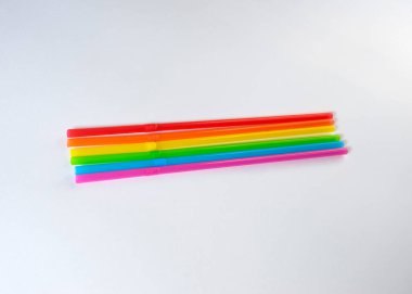 Açık gri arka planda yedi pipet gökkuşağı rengi yatıyor. Parlak renkler. Renkler LGBT insanlarının birleşme ve sevgisi kavramını sembolize ediyor.