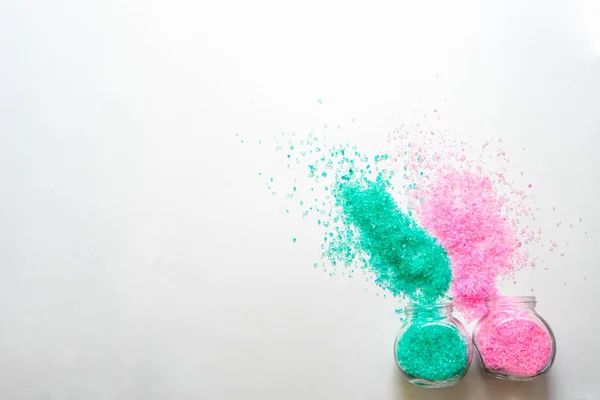 Açık pembe ve turkuaz banyo tuzlu iki şeffaf kavanoz. Beyaz arka planda yatay fotoğraf. Kişisel bakım ve spa için aksesuar konsepti. Bankalar yan yatar. Metin için boşluk