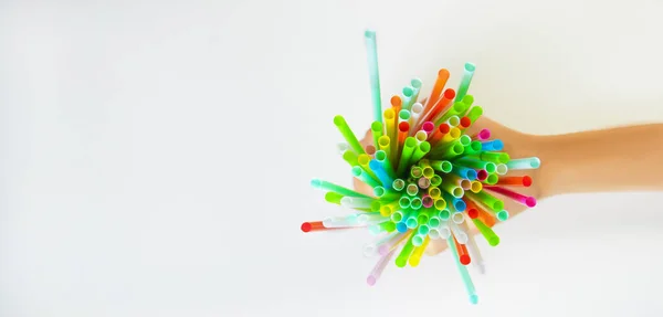 Elleri tek kullanımlık plastik pipetleri tutuyor. Yukarıdan bak. Farklı renkte nesneler. Tek kullanımlık konsept. Plastik yok de. Tek kullanımlık plastik atık. Metin için beyaz kopyalama alanı.