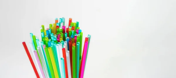 Resmin sol tarafında çok renkli plastik pipetler var. Beyaz arka planda, kopyalama alanındalar. Şenlik konsepti, parti, doğum günü. Üst Manzara. Yatay fotoğraf.