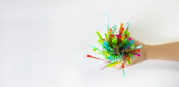 Elleri tek kullanımlık plastik pipetleri tutuyor. Yukarıdan bak. Farklı renkte nesneler. Tek kullanımlık konsept. Plastik yok de. Tek kullanımlık plastik atık. Metin için beyaz kopyalama alanı.