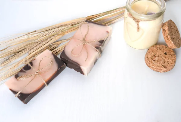 Düz kompozisyon, iki el yapımı kahverengi pembe sabun ile portakal rengi, kurumuş portakal dilimleri, gül çiçekleri, pastel vanila mumu ve ahşap desenli buğday başaklarıyla birlikte. Yatay fotoğraf. 