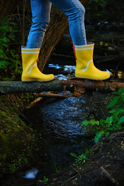 Sarı çizmeli kadın küçük bir dere boyunca yürür..