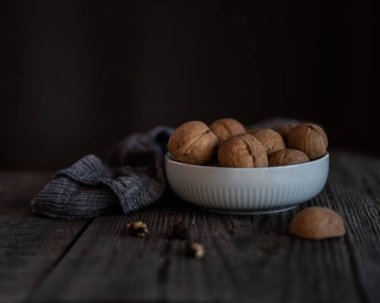 Koyu arkaplanda siramik bir kasede ceviz.