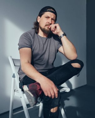 Stüdyoda gri arka planda oturan ciddi bir adam. Finans hakkında düşünüyorum. Serbest Çalışan.