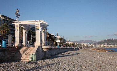 Baharda güneşli bir günde Nice 'te boş bir sahil ve uzaktaki denize bakan bir insan..