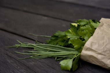 Maydanoz soğan ve kuşkonmaz. Koyu ahşap bir arka planda el işi torbası. 