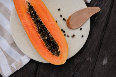 Keten bir masa örtüsü ve ahşap üzerinde beyaz bir tabakta kesilmiş papaya.