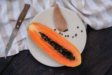 Keten bir masa örtüsü ve ahşap üzerinde beyaz bir tabakta kesilmiş papaya.
