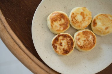 Ahşap bir masada beyaz bir tabakta süzme peynir krepleri.