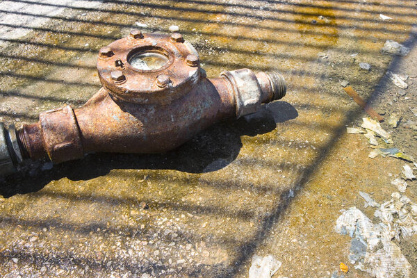 Старый и ржавый счетчик воды поставили на землю
