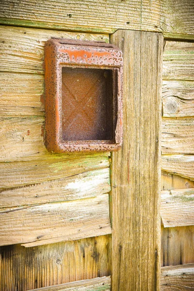 Old red mail box against a wooden door.