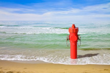 A hydrant at the seaside. Plenty of water: concept image clipart