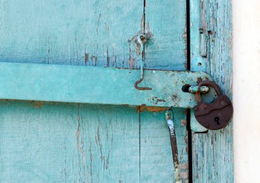 Mavi kapısında metal saplı metalik paslı bir kilit. Kapı eski ve sarılı..