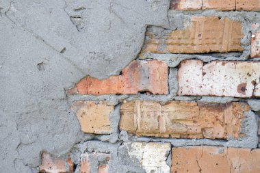 Duvarda kırmızı tuğla ve çimento var. Kıvrımlı ve yarım yamalak duvarcılık.