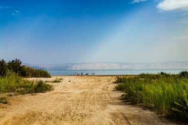 Galilee Denizi manzarası (Tiberias Gölü, Kinneret veya Kinnereth), lastik izleri ve duba iskelesi olan plaj. Dünyanın en düşük tatlı su gölü. İsrail.