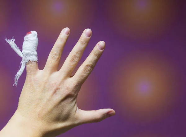 Close-up  a female hand with injured bleeding finger with bloody gauze on it.