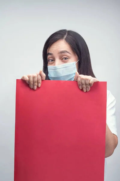Maskeli ve kırmızı tabelalı kadın mutlu görünüyor.