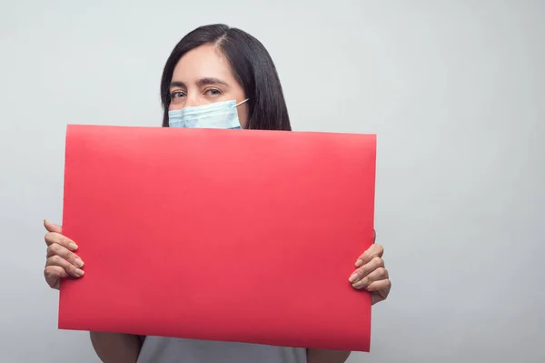 Maskeli ve kırmızı tabelalı kadın mutlu görünüyor.