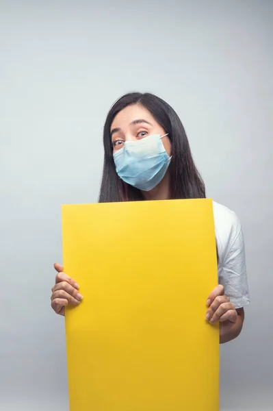 Maskeli ve sarı tabelalı kadın mutlu görünüyor.