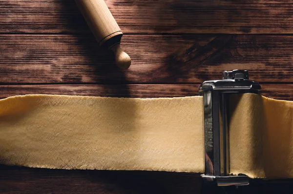 chef hands making homemade pasta with pasta maker