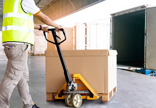 Worker courier unloading cargo pallet shipment goods, large package box, his using hand pallet jack load into a truck, Road freight transport, Warehouse industrial delivery shipment and logistics.