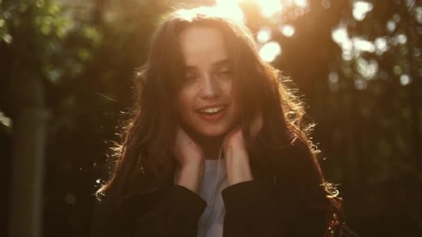 Close-up gezicht schot van een mooi meisje luisteren naar muziek terwijl genieten van de zon — Stockvideo