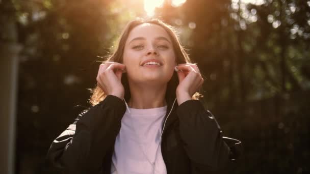 Close-up gezicht schot van een mooi meisje luisteren naar muziek terwijl genieten van de zon — Stockvideo