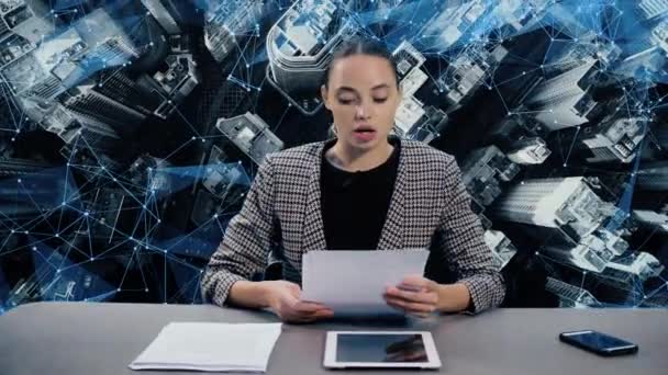 Closeup portrait of young girl sitting at a table in television newsroom. City on the background — Stock Video