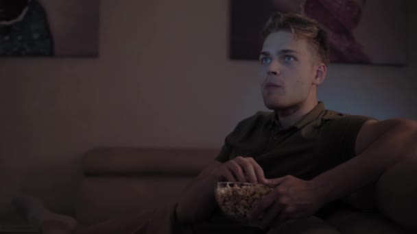 青い目の白人の感情的な若い男の肖像画ポップコーンを食べる — ストック動画