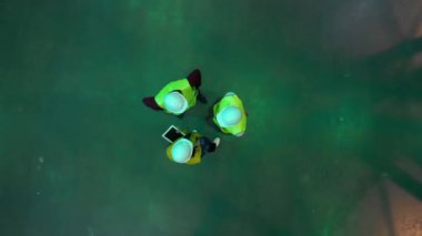 Tablet yöneticisi mühendisi ve ustabaşı olan yeşil yelekli ve miğferli işçiler