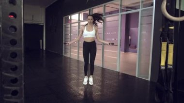 Spor salonunda ip atlama egzersizi yapan genç bir kadın. Sporcu kadın spor salonunda sıkı çalışıyor..